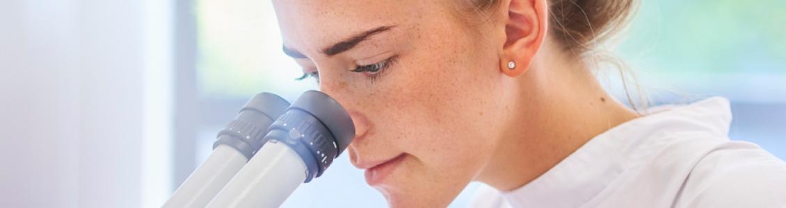 Woman looking down a microscope